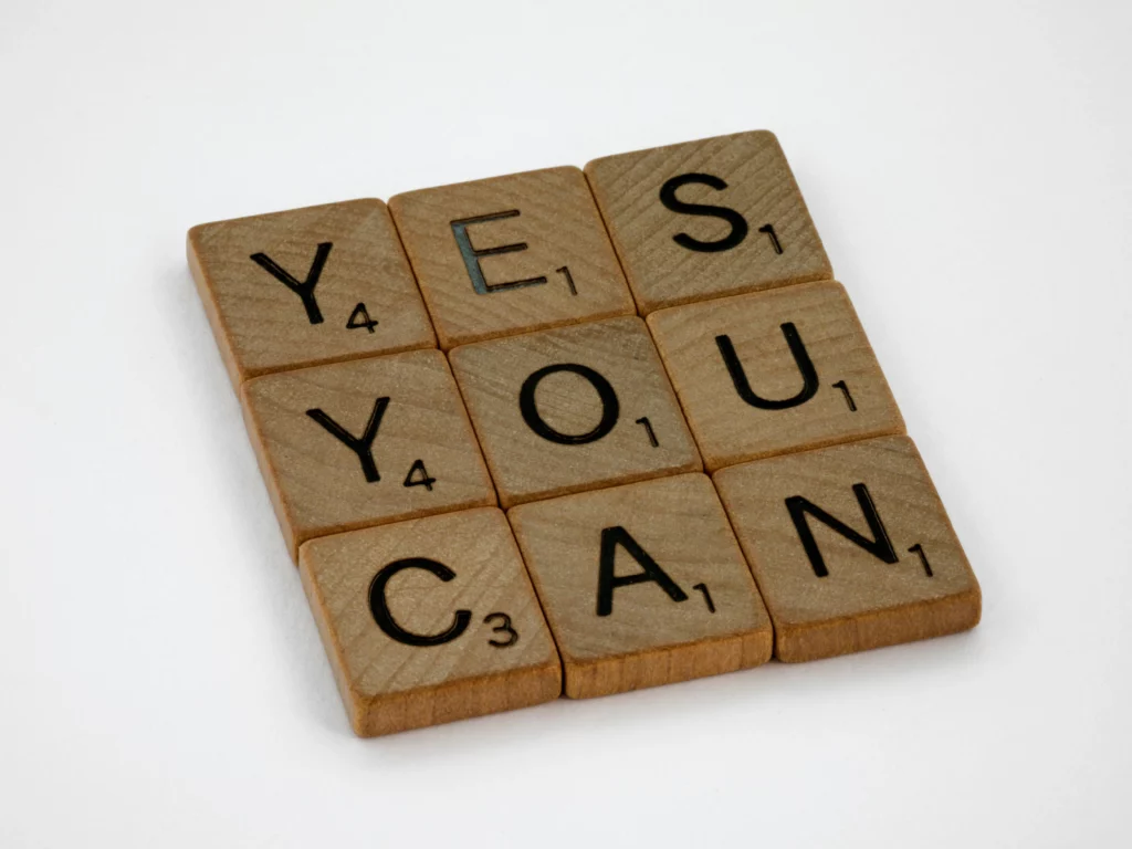 Drewniane litery układające słowo „YES YOU CAN”, pewność siebie (confidence) i wiary w swoje możliwości