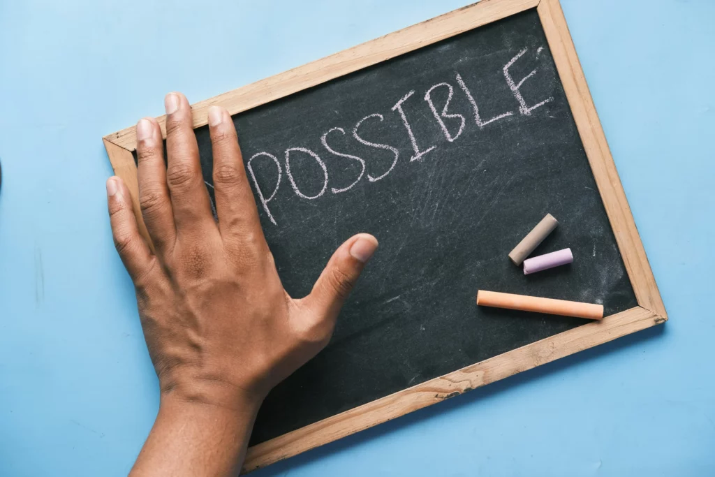 łoń na tablicy z napisem „impossible”, symbol przełamywania ograniczeń i pewność siebie (confidence)