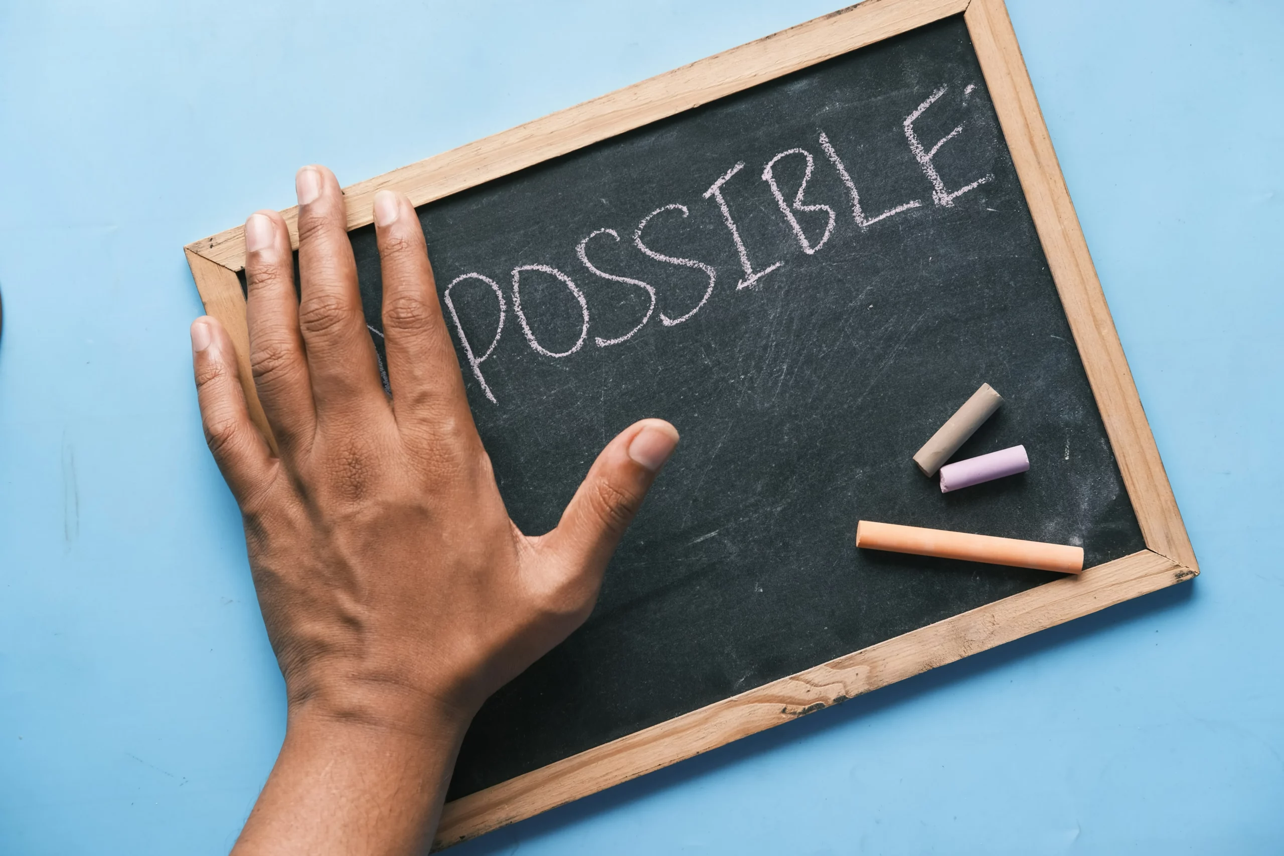 łoń na tablicy z napisem „impossible”, symbol przełamywania ograniczeń i pewność siebie (confidence)